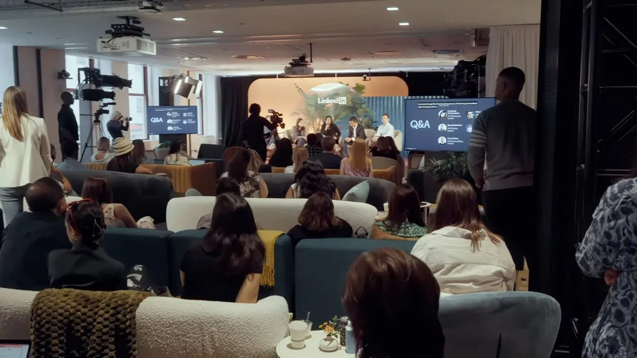 Audience seated in dim lounge watching Q&A presentation on stage screen