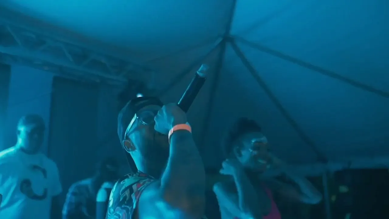 Performer holding microphone on stage under tent with blue lighting