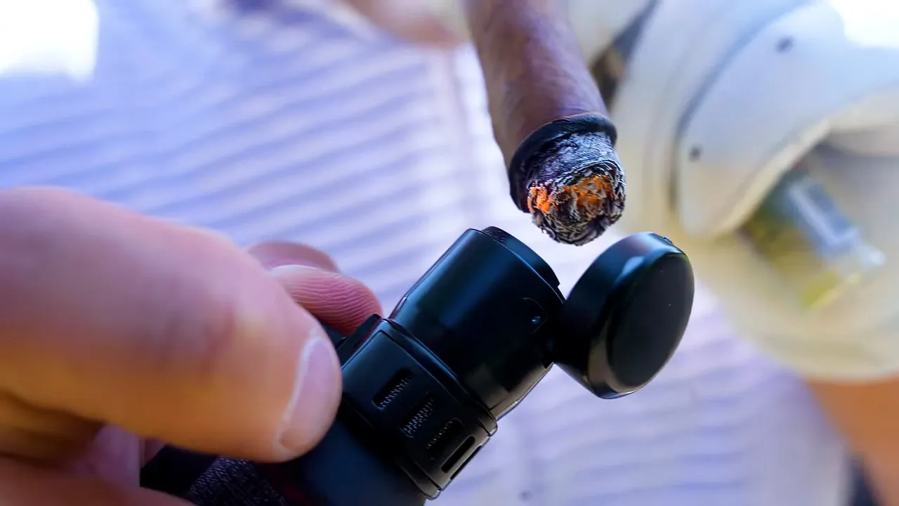 Close-up of hands cutting a cigar with a cigar cutter