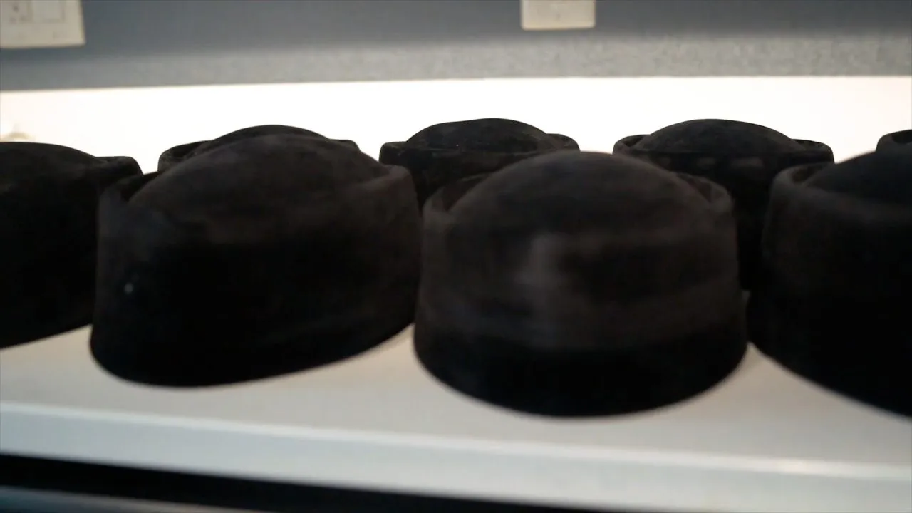 Row of black traditional velvet caps displayed on a bright surface indoors