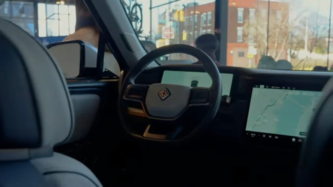 Interior of electric vehicle showing steering wheel and dashboard touchscreen, city buildings outside