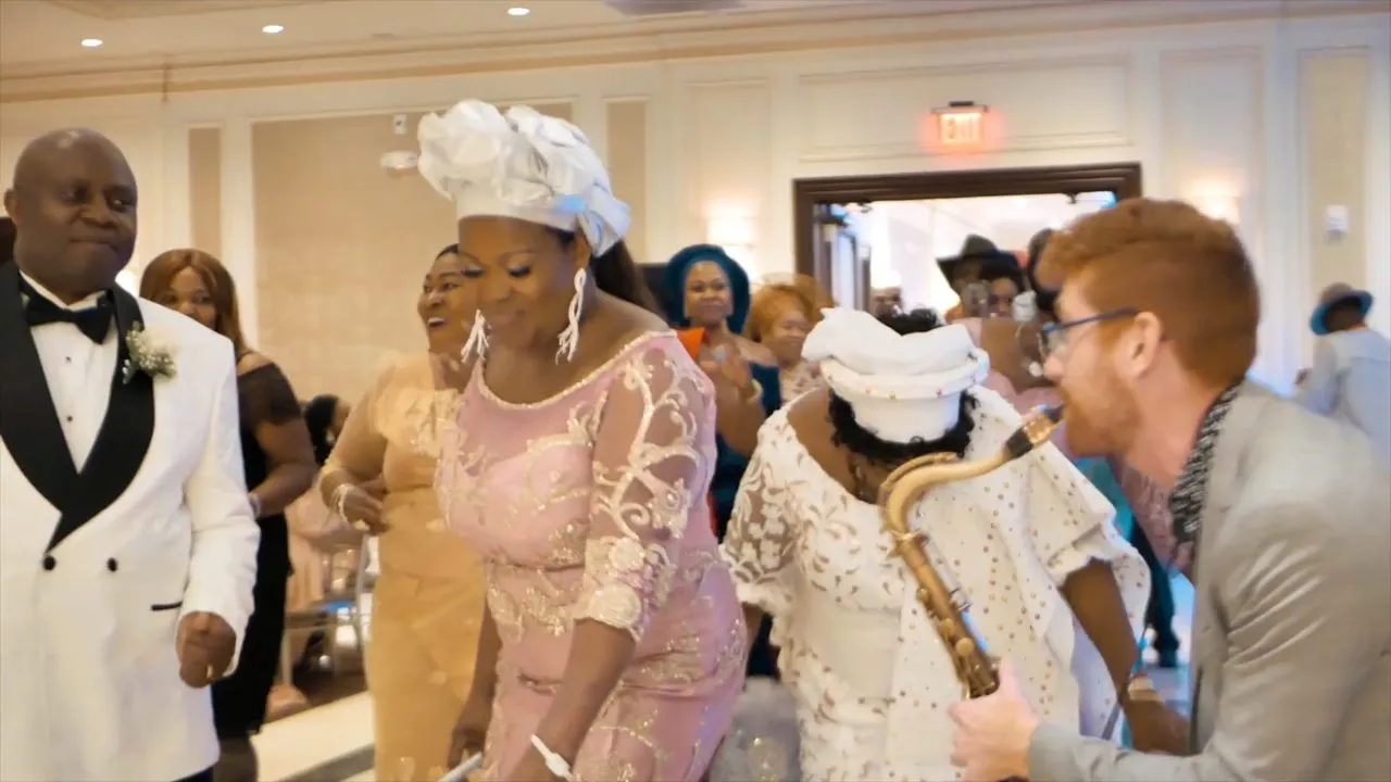 Guests in traditional African outfits and headwraps mingling at indoor reception
