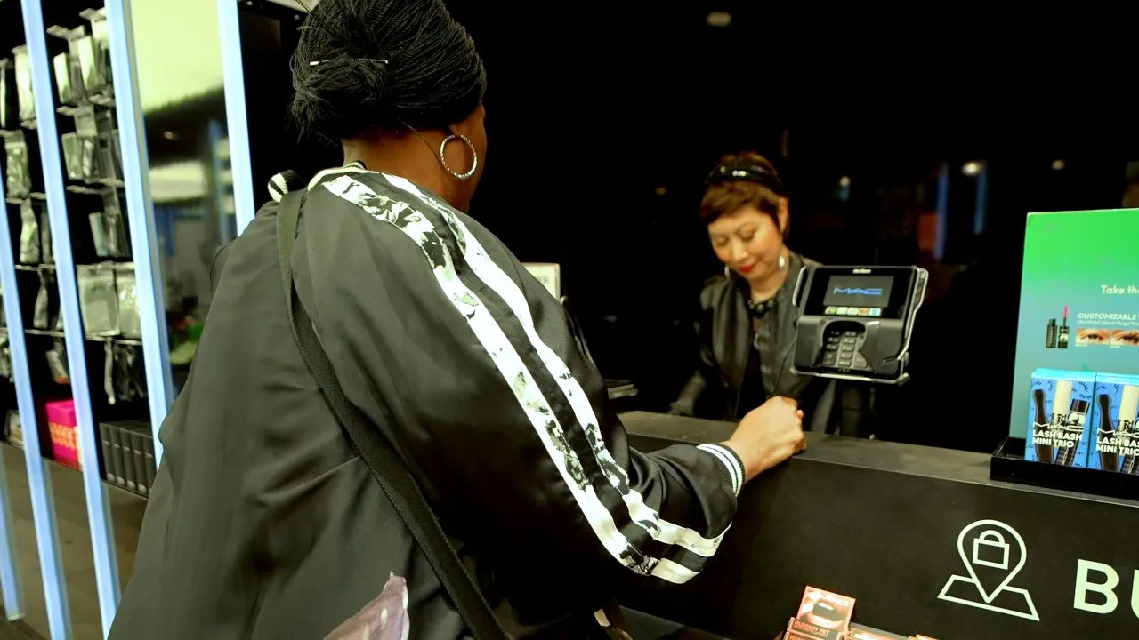 Customer at checkout counter paying while staff assists in store