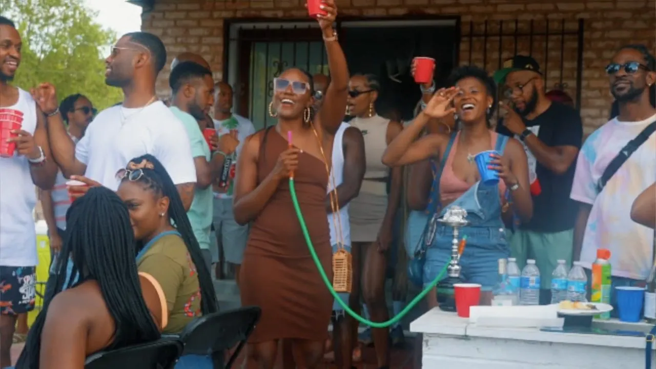 Crowd socializing with red cups and hookah at backyard house party, daytime