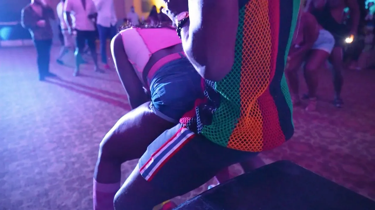 Dancer in colorful shorts moving on stage under purple club lighting