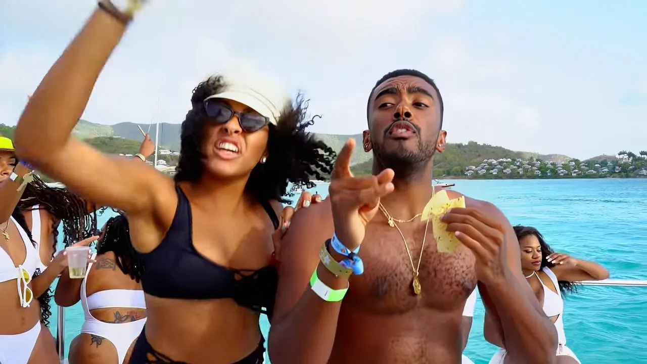 People dancing at daytime beach party by turquoise water, festive swimwear