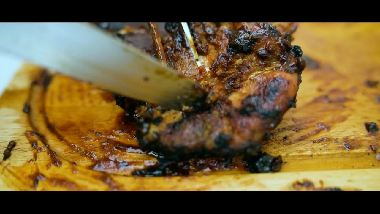 Close-up of grilled barbecue meat being cut on plate