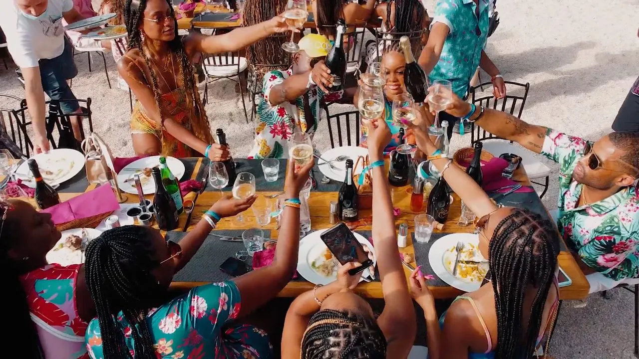 Overhead view of people toasting at outdoor table with food and drinks