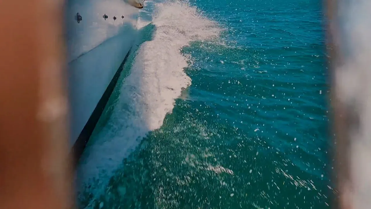 Boat wake and turquoise ocean water splashing beside a white vessel