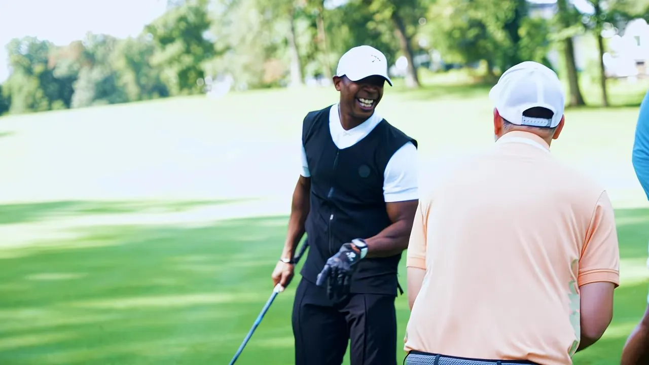 Two golfers talking on a sunny green golf course fairway outdoors