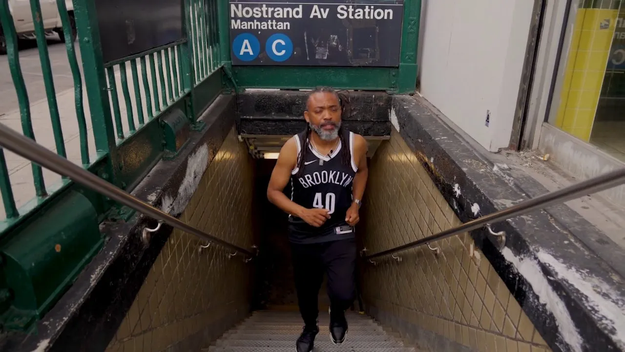 Person in Brooklyn jersey climbing stairs at Nostrand Av subway station, daytime