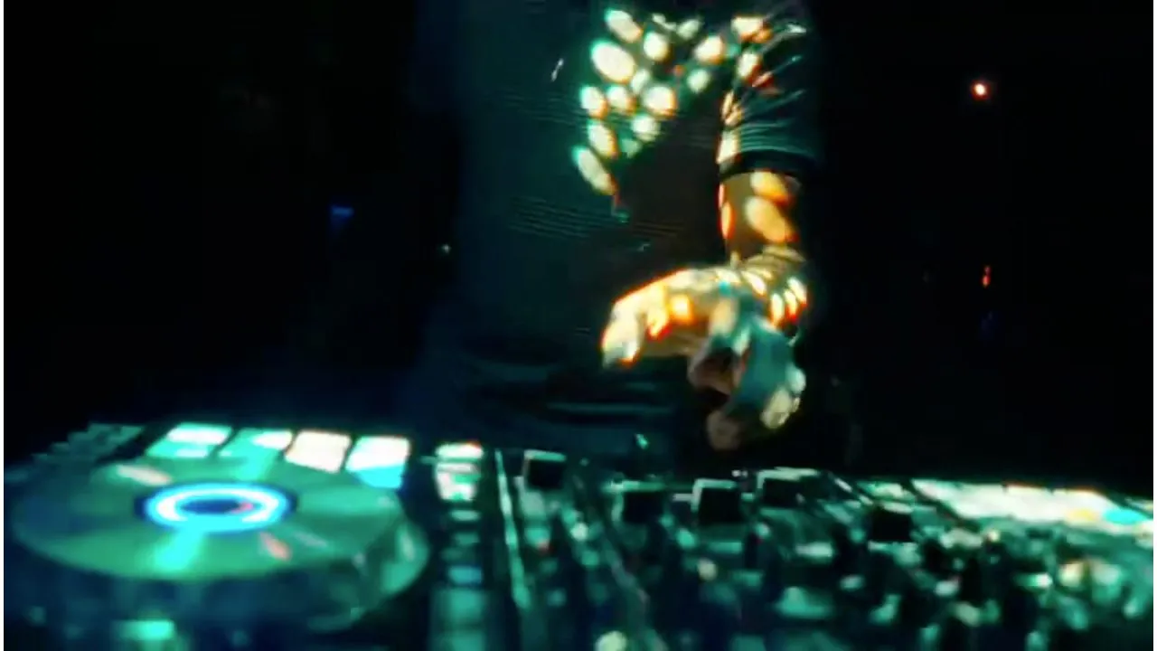 Hands on illuminated DJ controller mixer deck with green glowing buttons