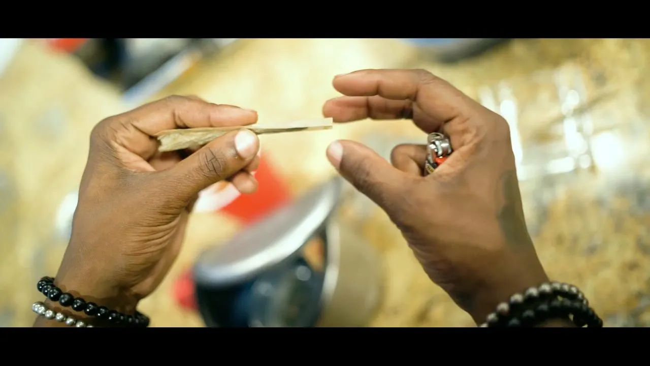 Hands rolling or preparing something over a can outdoors