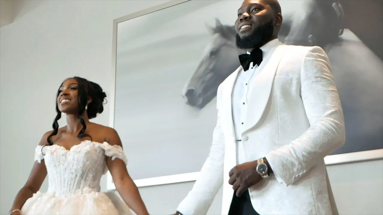 Bride in white gown beside groom in white tuxedo, horse artwork behind