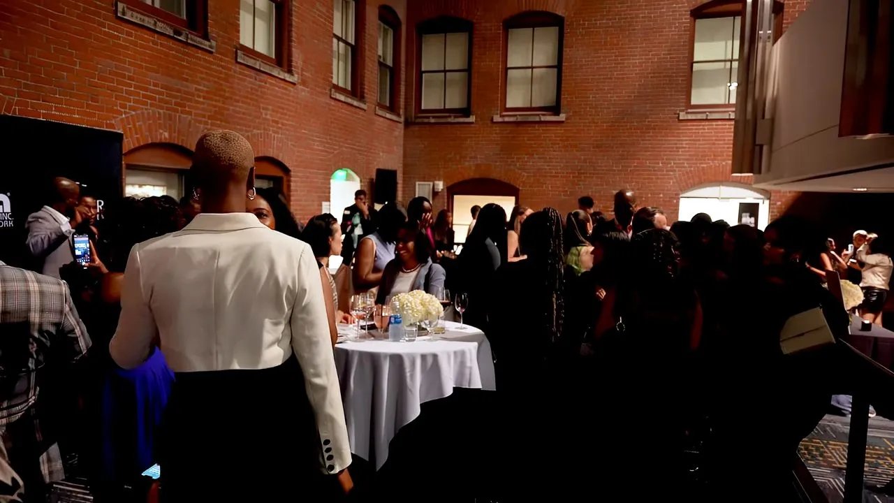 Crowded indoor reception in brick-walled venue with dressed guests standing