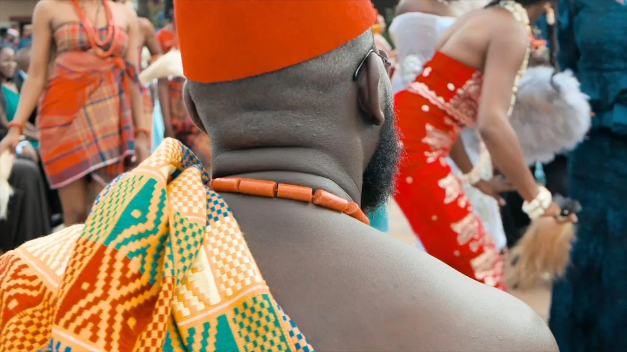 People in colorful African attire and coral beads at a crowded event